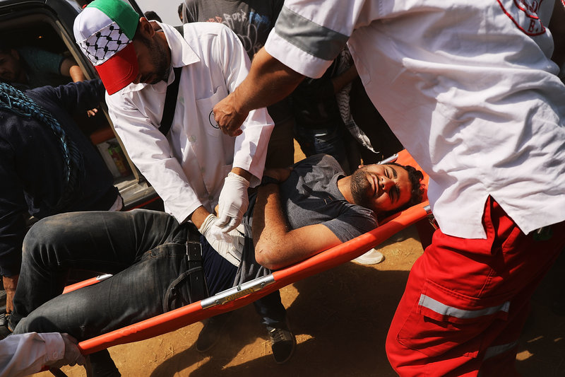 GAZA CITY, GAZA - MAY 14: A wounded Palestinian man is rushed to an ambulance at the border fence with Israel as mass demonstrations continue on May 14, 2018 in Gaza City, Gaza. Israeli soldiers killed at least 41 Palestinians and wounded over a thousand as the demonstrations coincided with the controversial opening of the U.S. Embassy in Jerusalem. This marks the deadliest day of violence in Gaza since 2014. Gaza's Hamas rulers have vowed that the marches will continue until the decade-old Israeli blockade of the territory is lifted. (Photo by Spencer Platt/Getty Images)